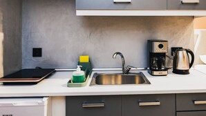 Eine moderne Küche mit grauen Schränken, einer Edelstahl-Spüle, einer Kaffeemaschine und einem Tablet auf der Arbeitsplatte.