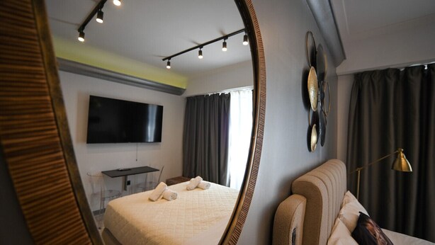 Une chambre d’hôtel avec un grand lit, un téléviseur à écran plat, un bureau et un miroir.