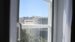 Une vue à travers la fenêtre d’un bâtiment doté d’une façade en verre, avec une structure classique en arrière-plan.