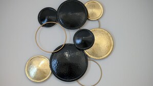 A geometric wall art piece with black and gold circular elements and gold rings. - Aura Suite by Zeus suites (Athina)