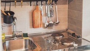 Una cocina con armarios blancos, electrodomésticos de acero inoxidable y utensilios colgando en la pared.
