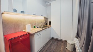 Cocina compacta con pileta, cafetera y un electrodoméstico rojo, probablemente un refrigerador pequeño.