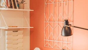 A workspace with a wooden desk, a chair, a lamp, and a geometric wall decoration.