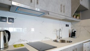 A modern kitchen with a stainless steel kettle, a coffee machine, and a built-in sink.