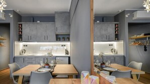 A modern kitchen with grey cabinets, a wooden dining table, and a mirrored backsplash.