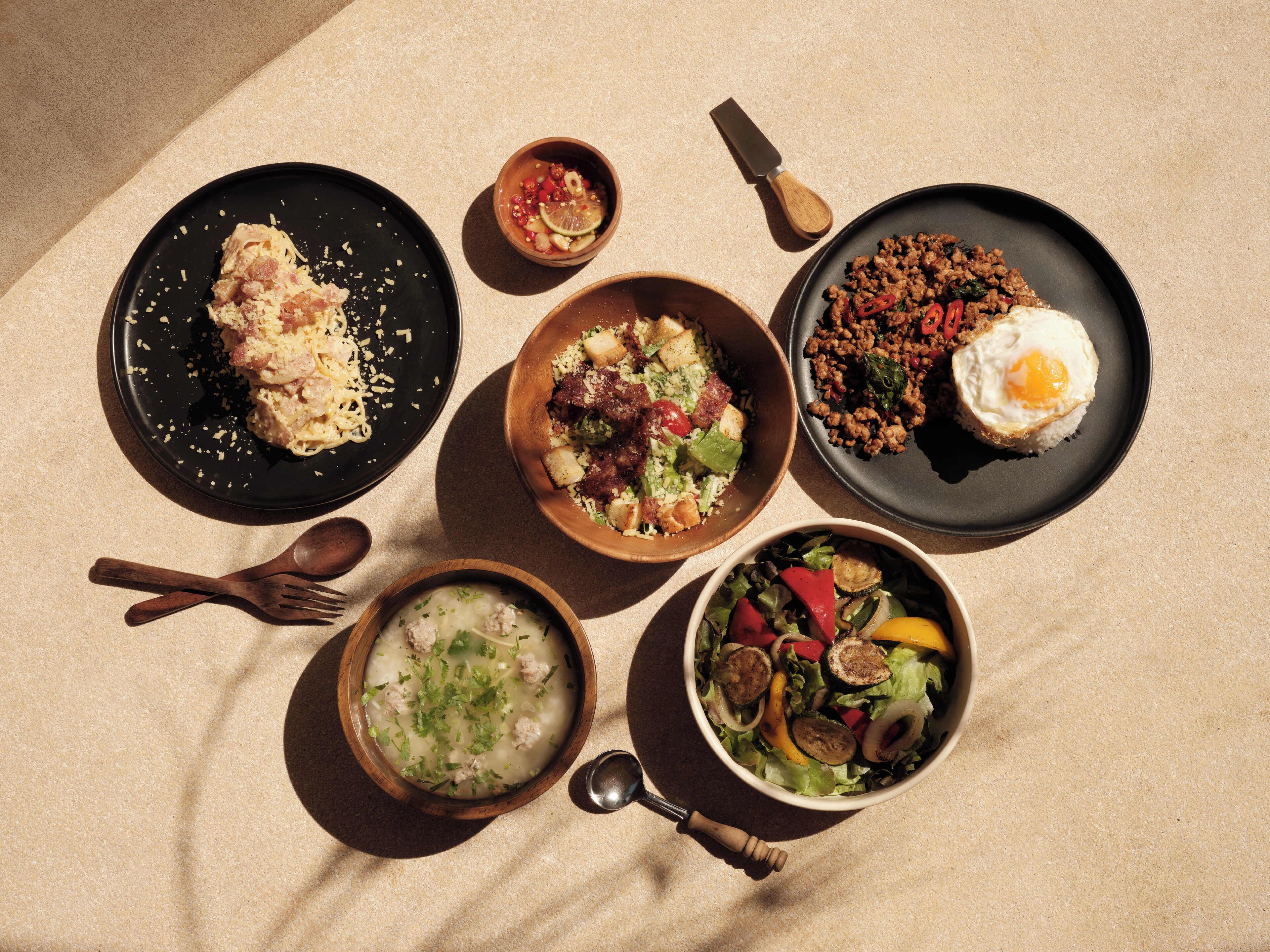 Una mesa con diversos platos, incluyendo pasta, ensalada y un tazón de sopa.