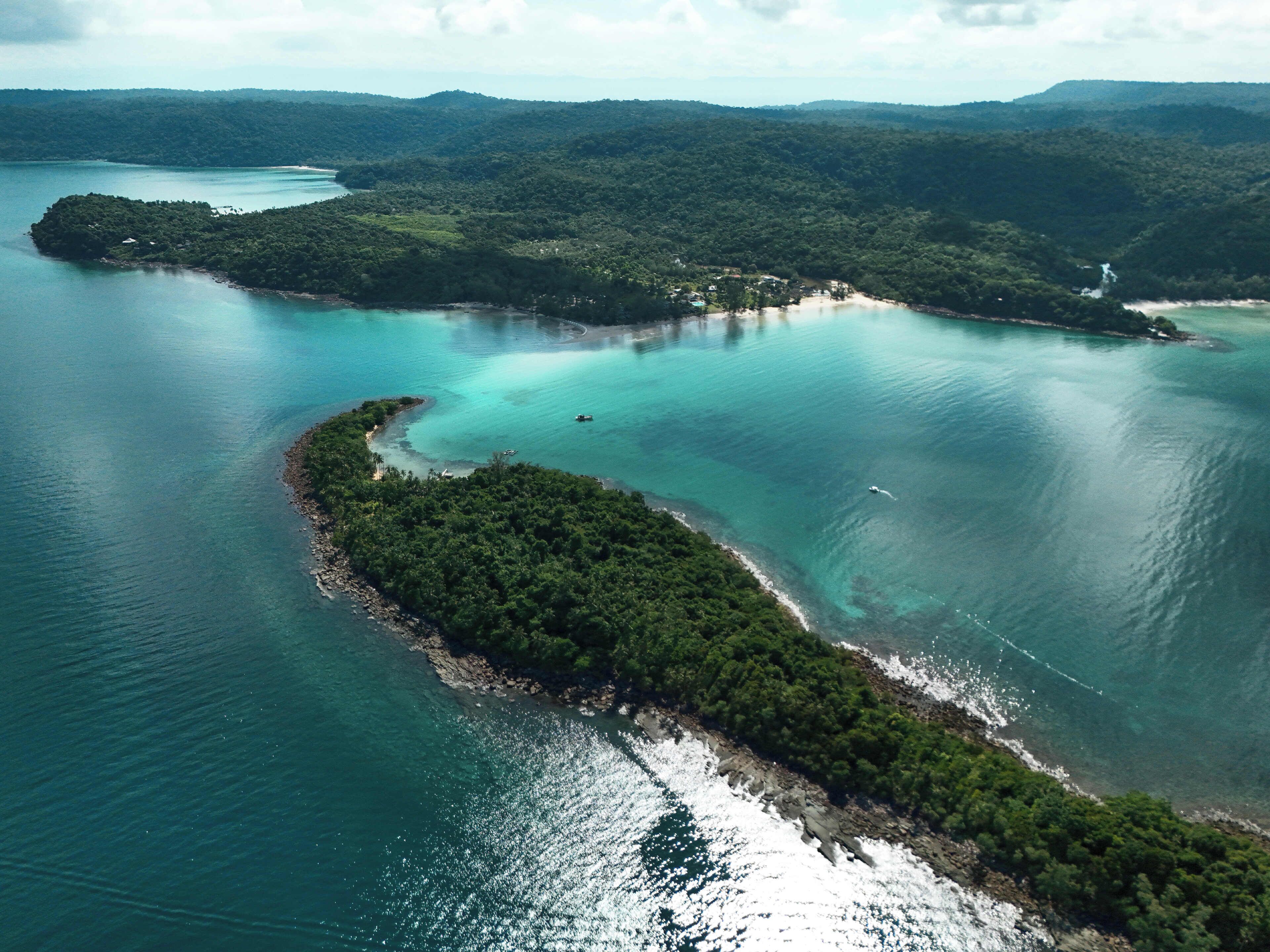 An aerial view of a coastal area with a small island surrounded by turquoise waters.