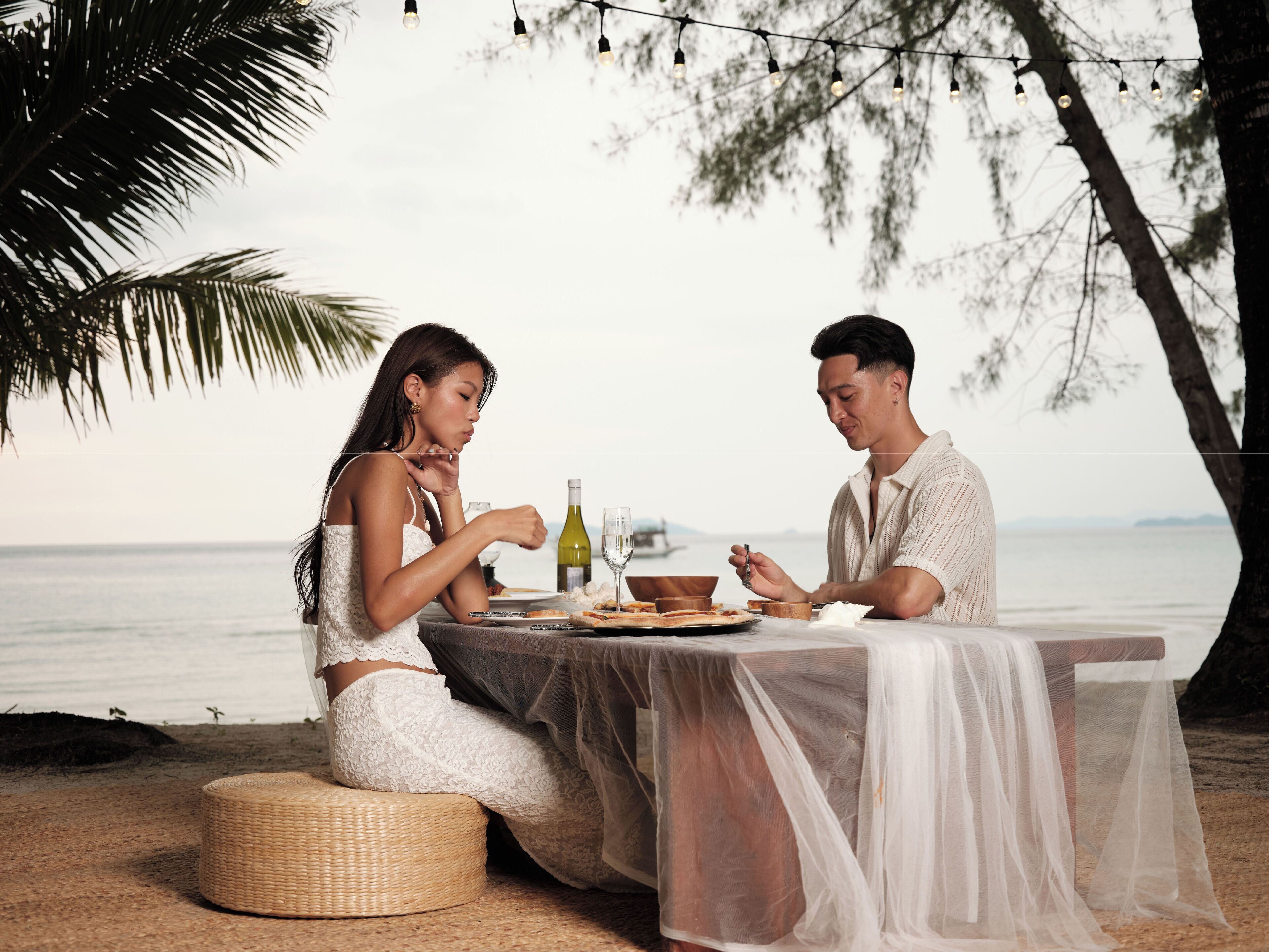 Mesa de comedor al aire libre con vista al mar, una botella de vino y un plato de comida.