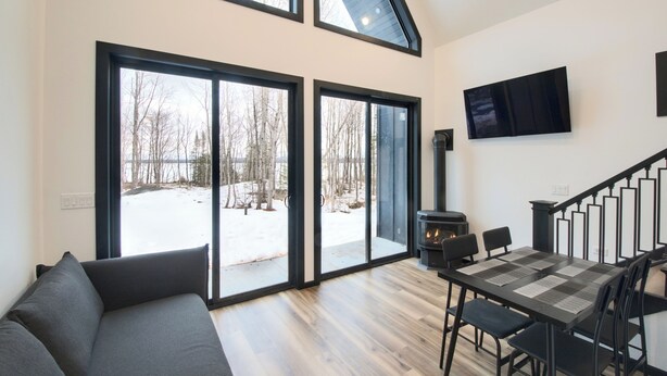 A modern living room with a large window, a fireplace, and a dining area.