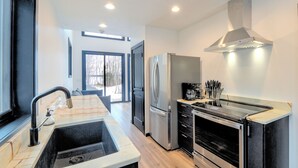 A modern kitchen with a stainless steel refrigerator, oven, and a range hood.