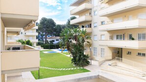 Un immeuble résidentiel à plusieurs étages, doté de balcons, d’une piscine et d’une pelouse bien entretenue.