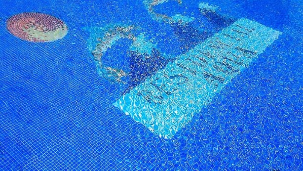 Une piscine dont l’eau est claire et dont les bords sont bien visibles.