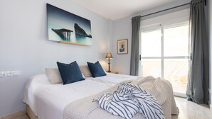 Une chambre à coucher avec un lit, un tableau, une lampe et une vue sur l’extérieur.