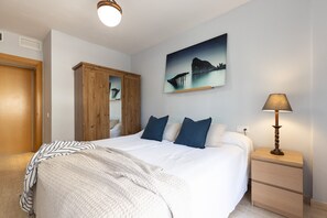 Une chambre à coucher avec un lit, une table de chevet, une lampe, une armoire et un tableau au mur.