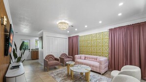 A modern living room with a sofa, two armchairs, a coffee table, and a decorative wall panel.