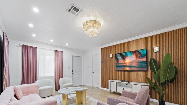 A modern living room with a large TV, comfortable seating, and a decorative wall panel.