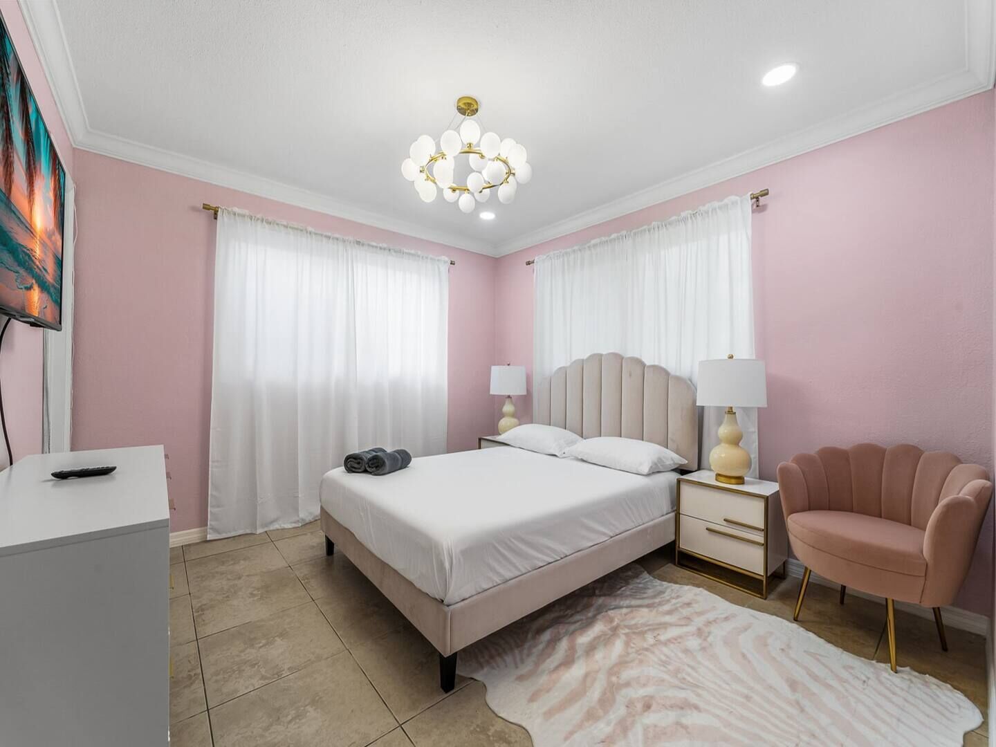 A bedroom with a bed, bedside tables, a chair, a rug, and a ceiling light.