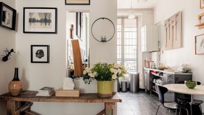 A kitchen with a wooden table, a vase with flowers, and framed pictures on the wall. - Playful Atelier, by Veeve (Paris)