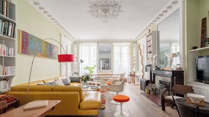 A spacious living room with a yellow sofa, modern chairs, a wooden coffee table, and a fireplace. - Playful Atelier, by Veeve (Paris)