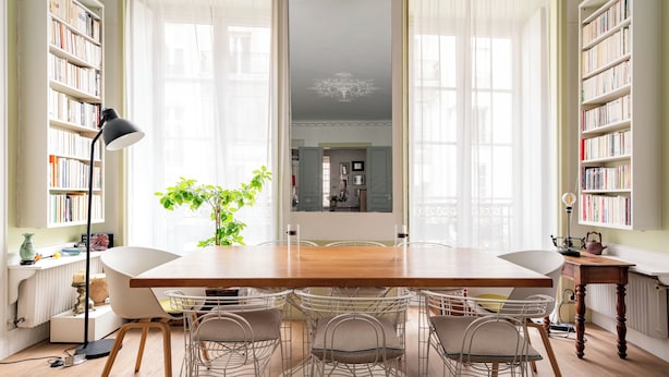 A dining area with a wooden table, white chairs, a potted plant, and bookshelves. - Playful Atelier, by Veeve (Paris)