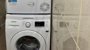 A stacked washer and dryer unit in a tiled room. - Tirent Apartment-Studio Central (Tirana)