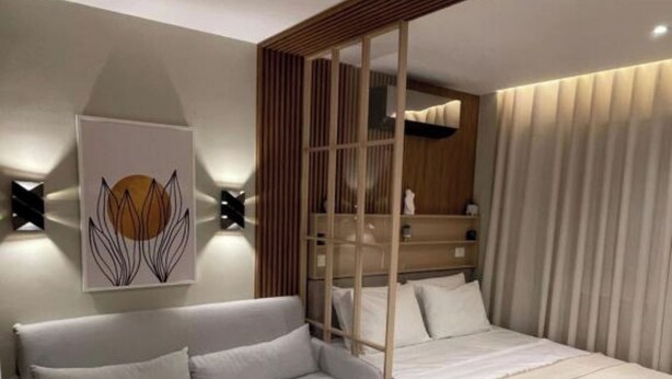 A modern bedroom with a sofa, a bed, a wooden panel wall, and a wall-mounted artwork. - Tirent Apartment-Studio Central (Tirana)