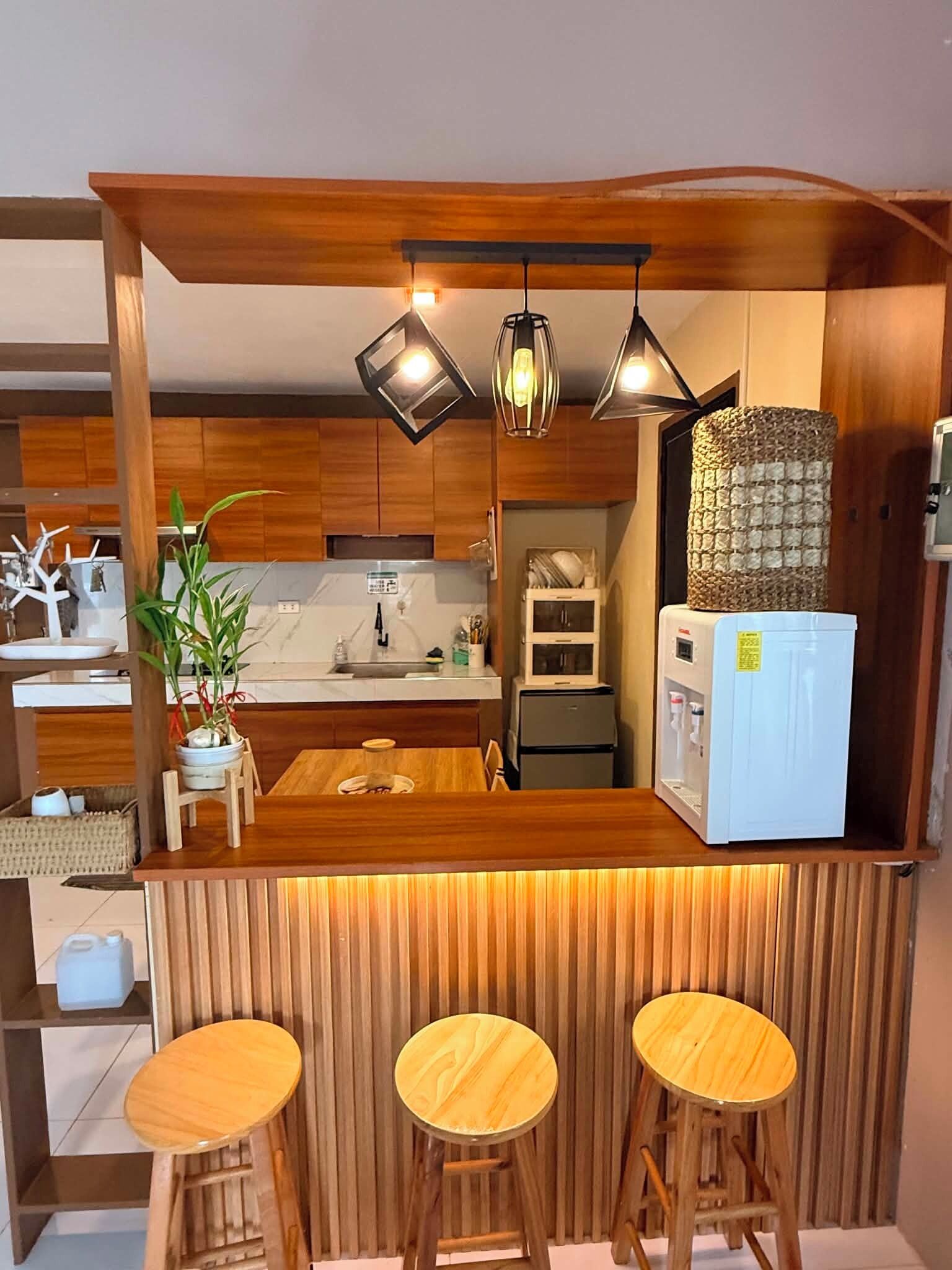A compact kitchen with a wooden island, bar stools, and pendant lighting.