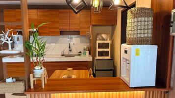 A compact kitchen with a wooden island, bar stools, and pendant lighting.