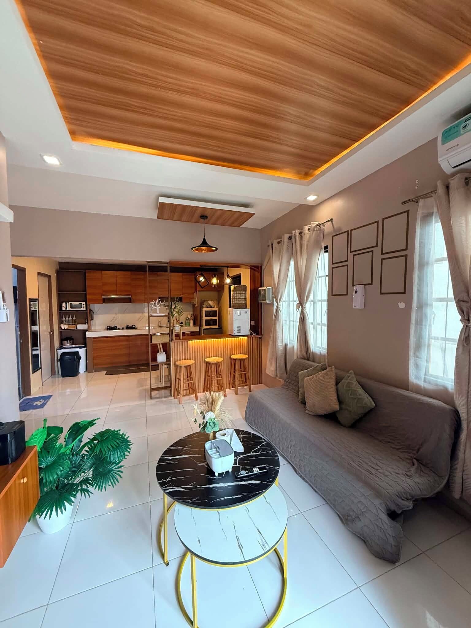 A modern living room with a sofa, a round coffee table, and a kitchen area in the background.