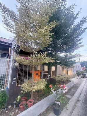 A residential building with a fenced yard, potted plants, and a small outdoor seating area.