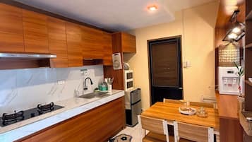 A compact kitchen with wooden cabinets, a built-in stove, and a dining area with a table and chairs.