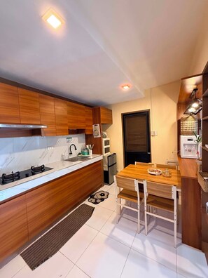 A compact kitchen with wooden cabinets, a built-in stove, and a dining area with a table and chairs.
