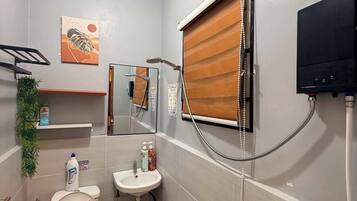 Un baño pequeño con inodoro, lavamanos y ducha.
