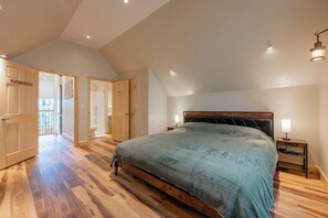 A bedroom with a large bed, wooden flooring, and a sloped ceiling. - Peaceful A-frame cabin with hot tub, forest views, modern comfort, and total privacy in nature. (Radford)