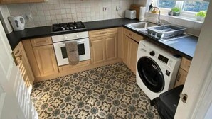 A compact kitchen with a stove, oven, sink, and washing machine. - 3 Bed House - Sleeps 6 - Parking - Wifi (Maidstone)
