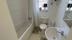 A bathroom with a bathtub, toilet, sink, and a window with a view of the outside. - 3 Bed House - Sleeps 6 - Parking - Wifi (Maidstone)
