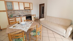 A compact living space with a kitchenette, dining table, chairs, and a sofa. - Apartments with spectacular views of Budoni Bay 3 min. from the sea-4 places (Malamurì)