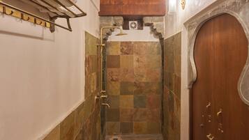 A bathroom with a shower, tiled walls, a wooden door, and a towel rack.