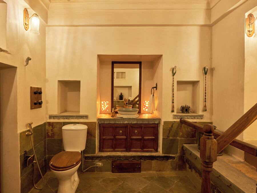 Une salle de bain avec des toilettes en bois, un lavabo avec un miroir au-dessus et un espace douche.