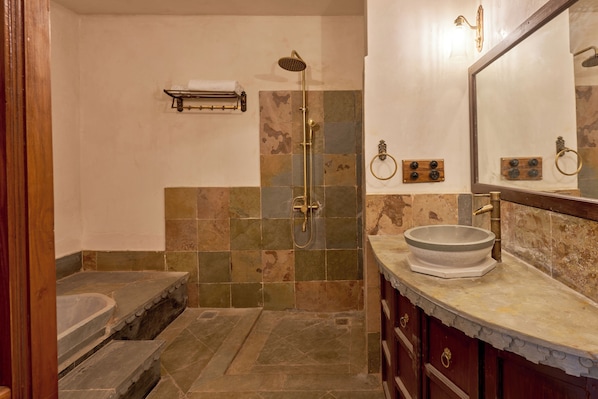 A bathroom with a stone shower, a sink with a basin, and a mirror with a wooden frame. - Kaladwas Lal Haveli (Udaipur)