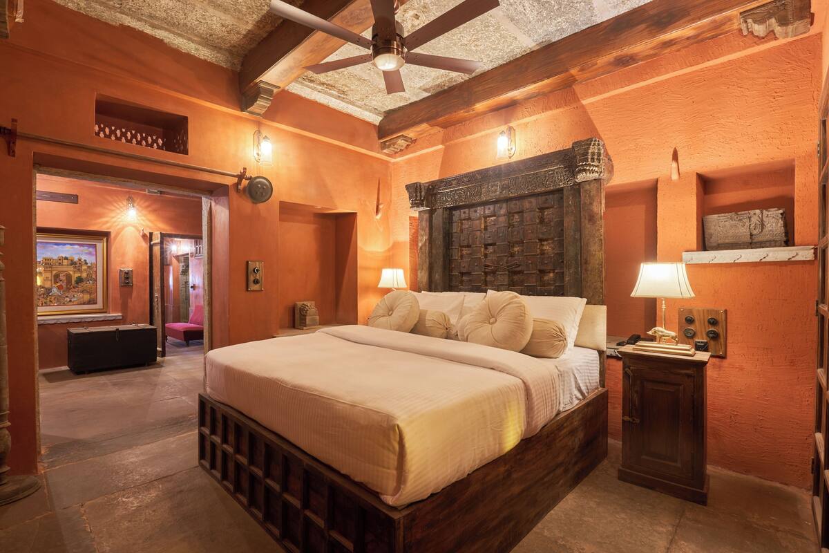 A bedroom with a large bed, wooden headboard, and a ceiling fan.