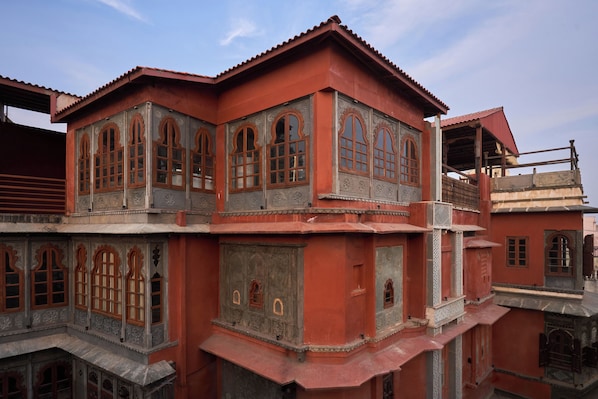 Um edifício com vários andares e detalhes arquitetônicos elaborados, incluindo janelas em arco e trabalhos em pedra decorativos.