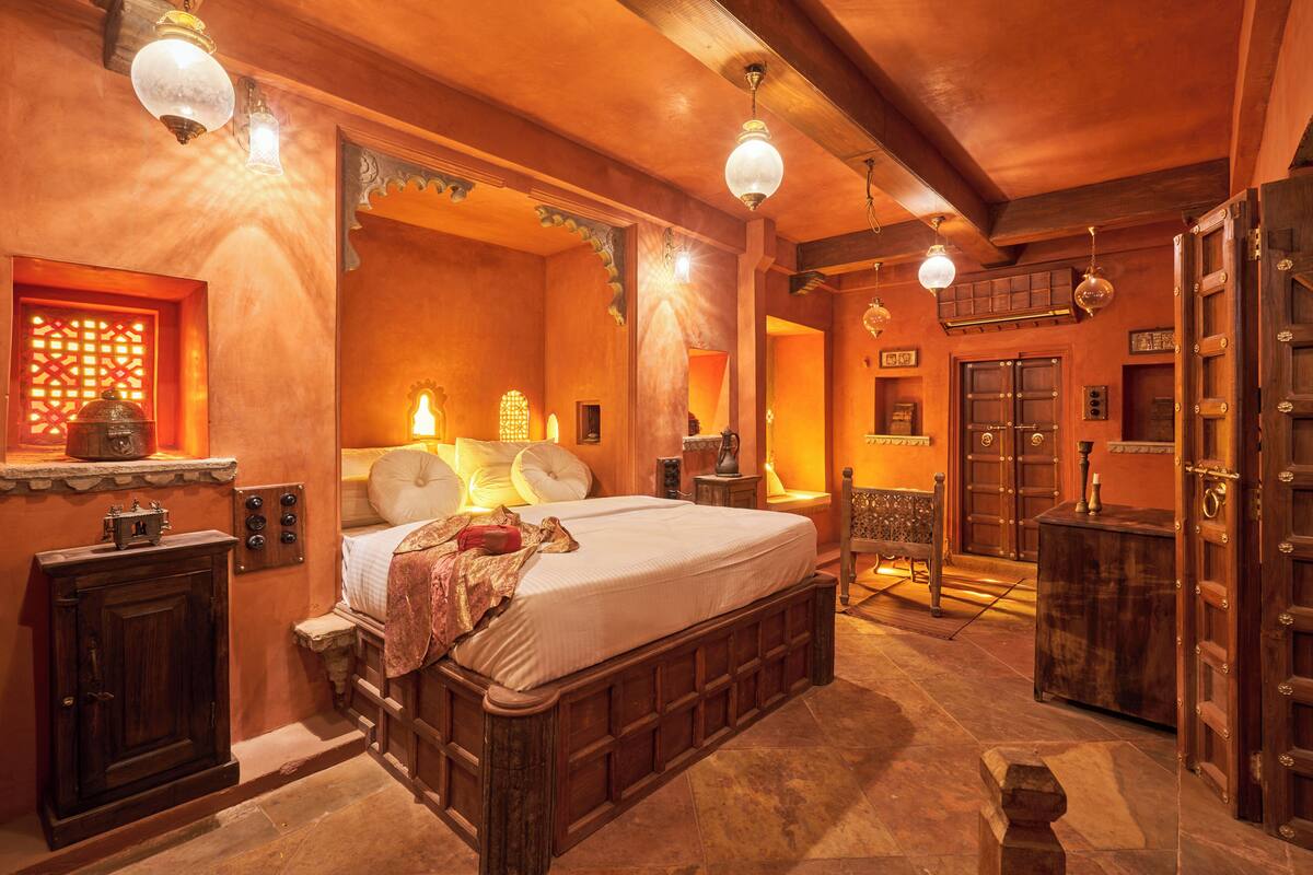 A traditional room with a large bed, wooden furniture, and a decorative wall.