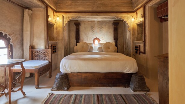 A traditional room with a large bed, a wooden desk, and a small table. - Kaladwas Lal Haveli (Udaipur)