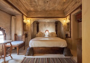 A traditional room with a large bed, a wooden desk, and a small table. - Kaladwas Lal Haveli (Udaipur)