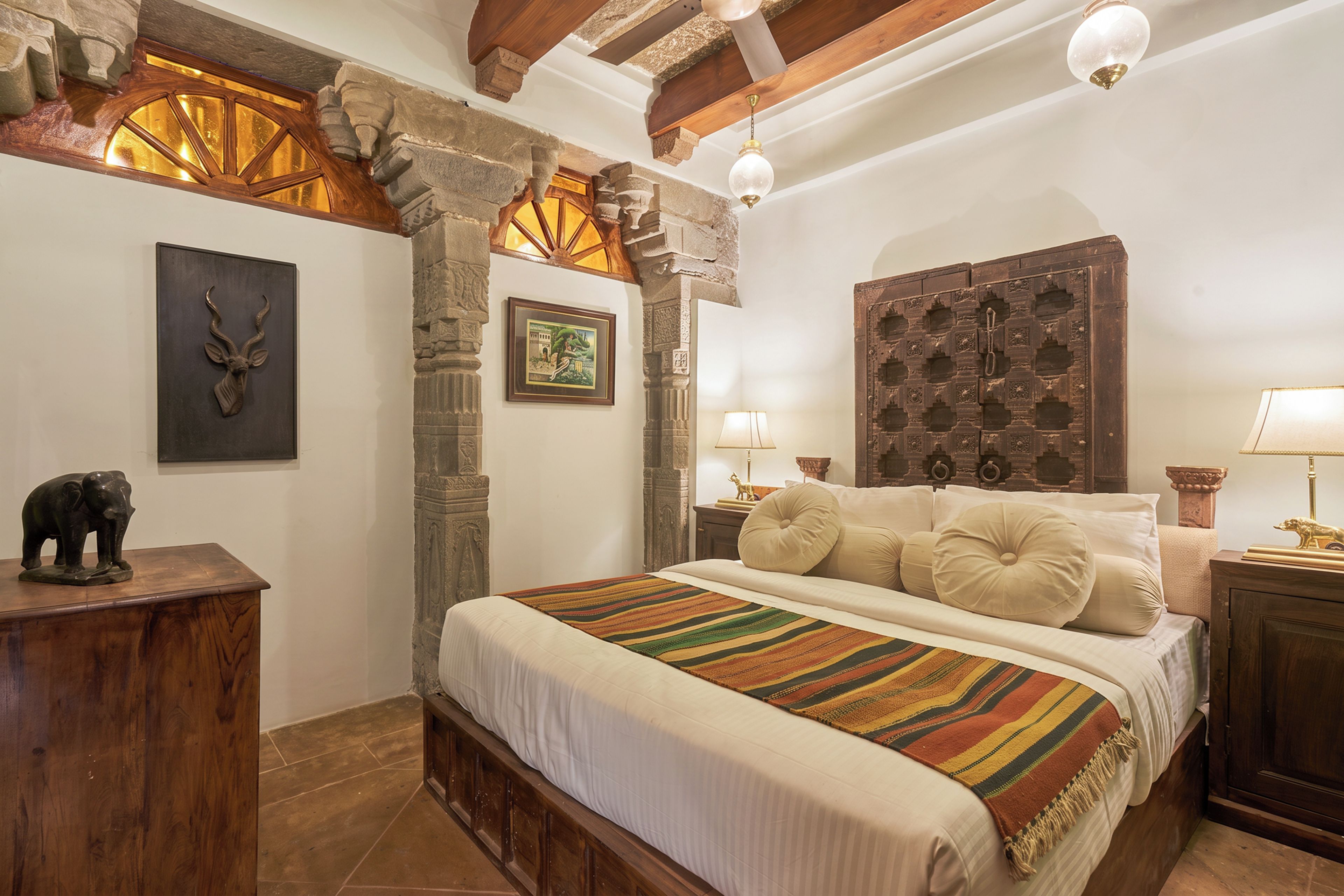 Un dormitorio con cama, cabecera de madera, pared de piedra y un cuadro enmarcado.