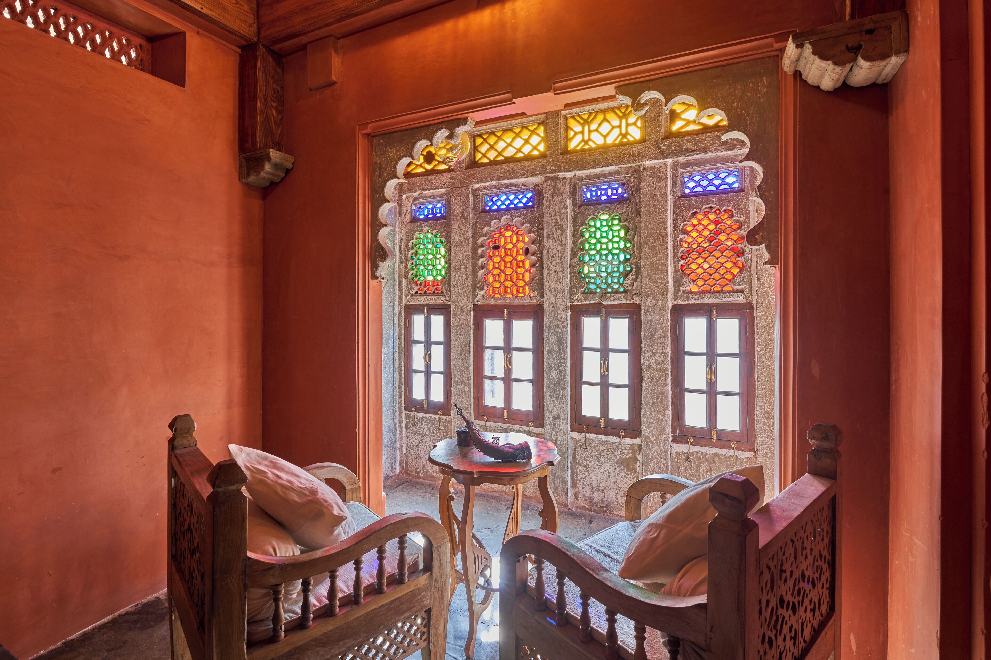 Una habitación de diseño tradicional, con una cama de madera y cabecera, una mesita redonda pequeña y dos sillas.