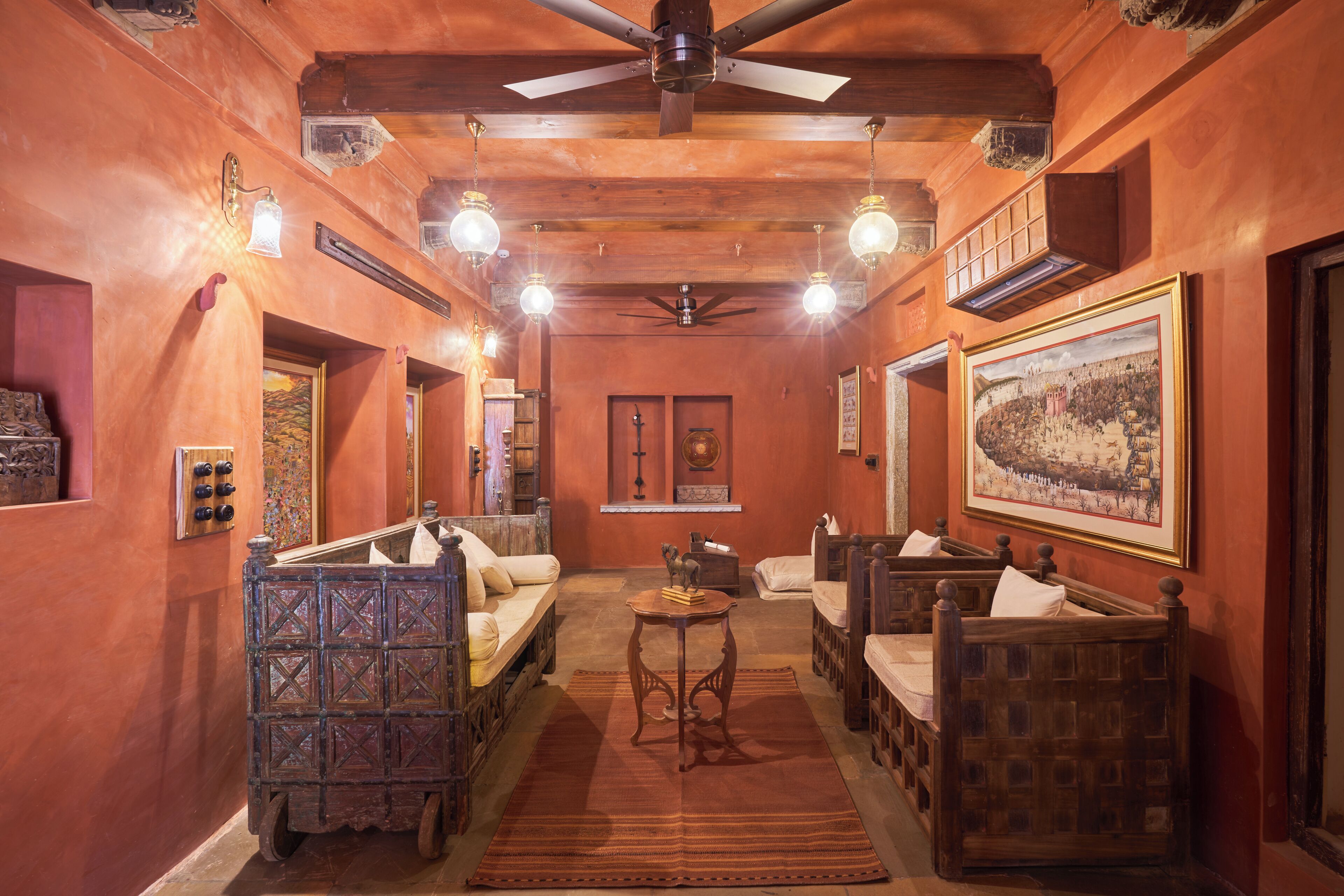 A room with wooden furniture, a ceiling fan, and wall-mounted lights.