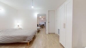 A bedroom with a bed, bedside table, lamp, wardrobe, and a mirror. - Fully-equipped apartment Vieux Lyon (Lyon)