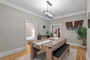 Ein geräumiges Zimmer mit Holztisch, Bank und einer modernen Pendelleuchte.